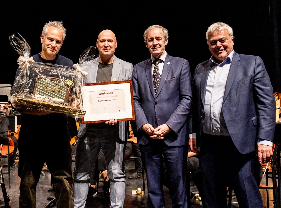 Burgemeester Lieven Dehandschuuter en schepen van Cultuur Filip Baeyens reiken de titel van culturele ambassadeur van Sint-Niklaas uit aan Stijn Van de Voorde.